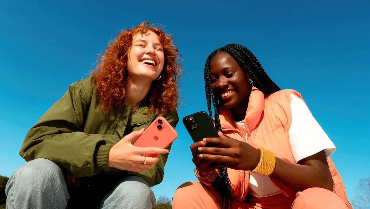 Dos mujeres sentadas al sol con sus teléfonos, contra un cielo azul