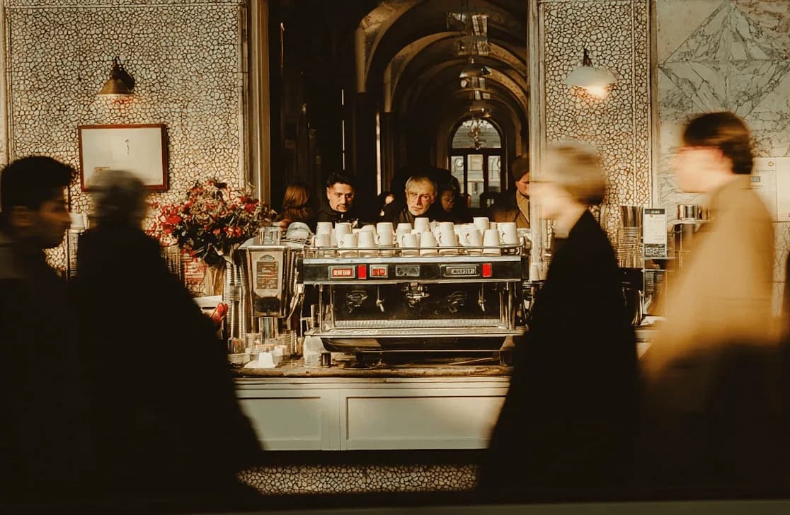 La barra de una cafetería de especialidad con la máquina de espresso y gente esperando